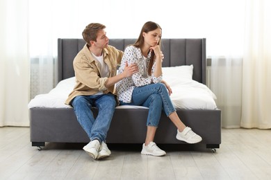 Photo of Man apologizing to his offended girlfriend on bed at home