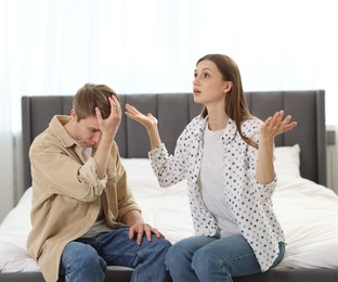 Photo of Man apologizing to his wife while she resenting on bed at home
