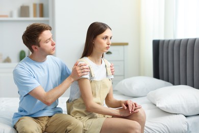 Photo of Man apologizing to his offended girlfriend on bed at home