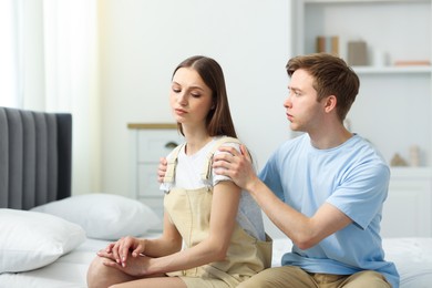 Photo of Man apologizing to his offended girlfriend on bed at home