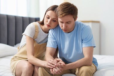 Photo of Young woman apologizing to her offended boyfriend on bed at home