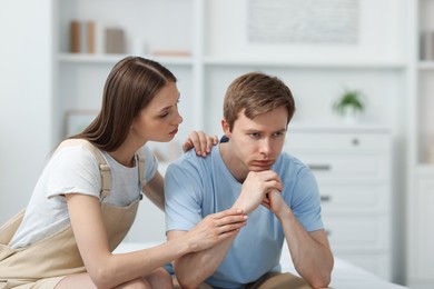 Photo of Young woman apologizing to her offended boyfriend at home