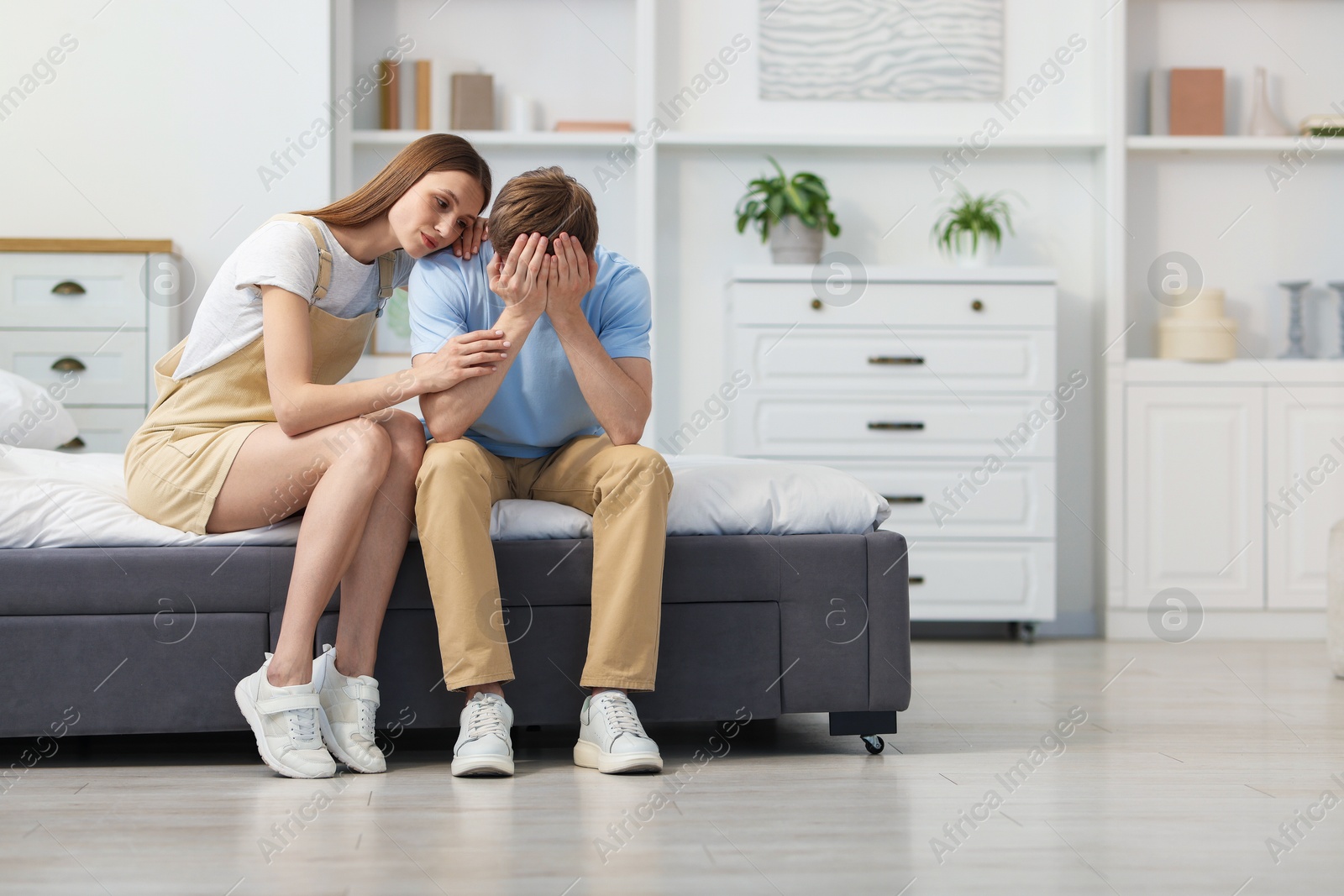 Young woman apologizing to her frustrated boyfriend on bed at home Photo of Young woman apologizing to her frustrated boyfriend on bed at home