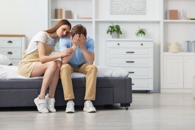 Photo of Young woman apologizing to her frustrated boyfriend on bed at home