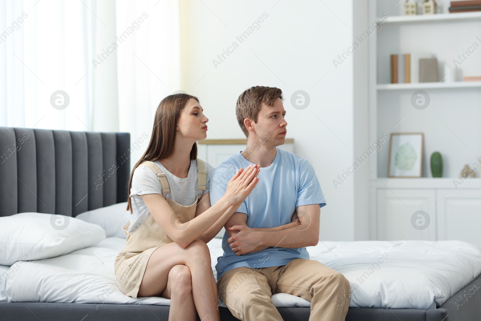 Young woman apologizing to her offended boyfriend on bed at home Photo of Young woman apologizing to her offended boyfriend on bed at home