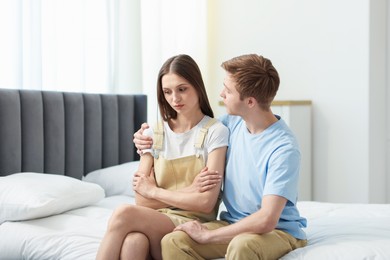 Photo of Man apologizing to his offended girlfriend on bed at home