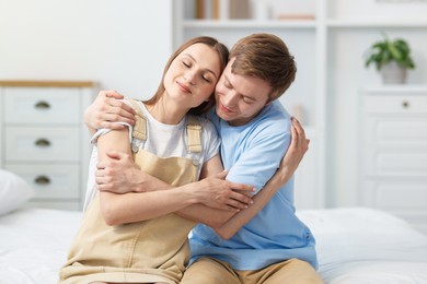 Photo of Lovely couple hugging after apology on bed at home
