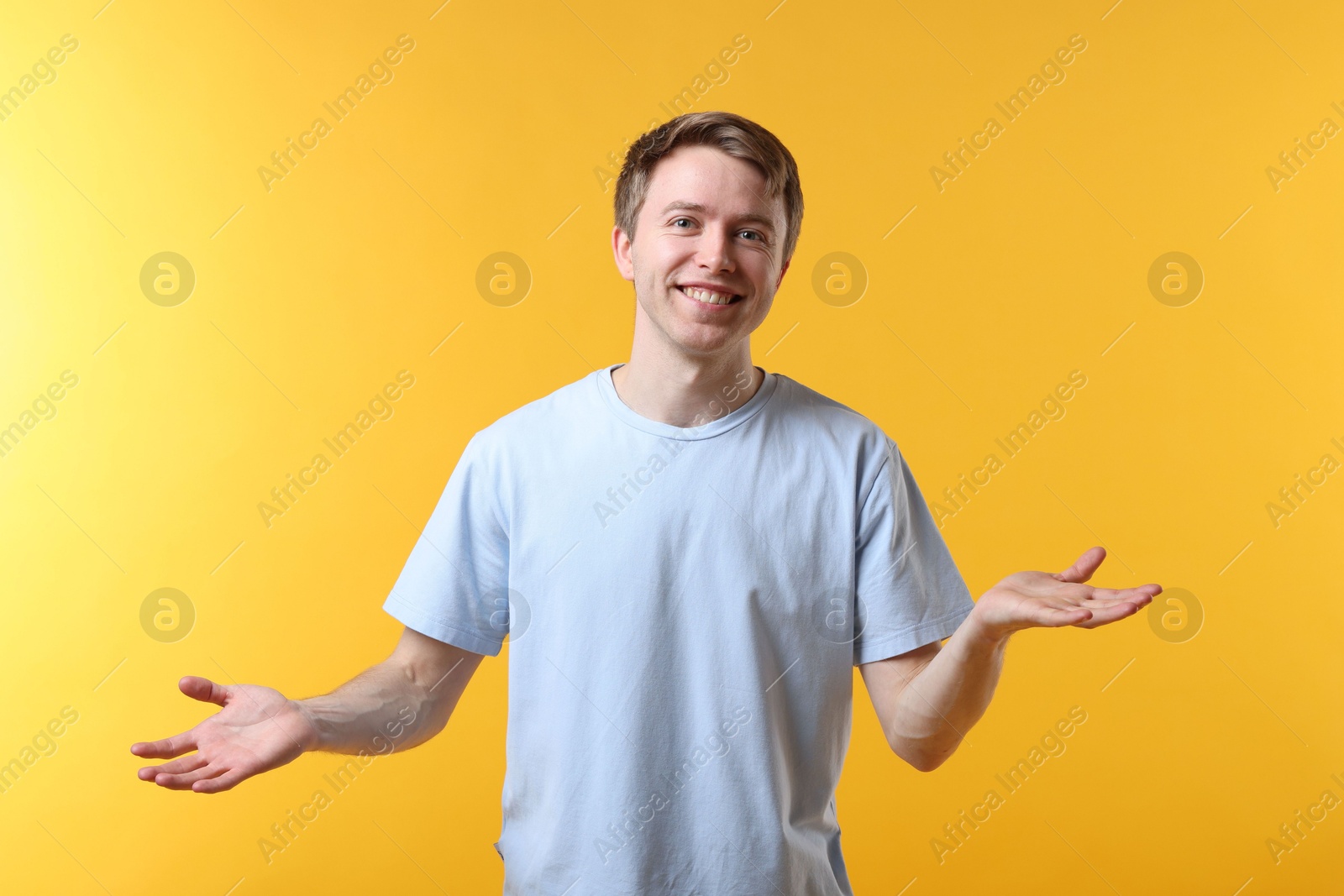 Portrait of smiling man apologizing on yellow background Photo of Portrait of smiling man apologizing on yellow background