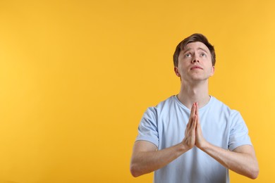 Photo of Man with clasped hands apologizing on yellow background. Space for text