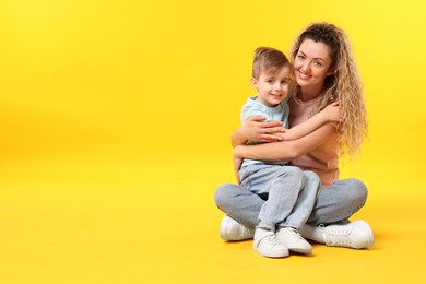Photo of Family. Happy mother and her son on yellow background. Space for text