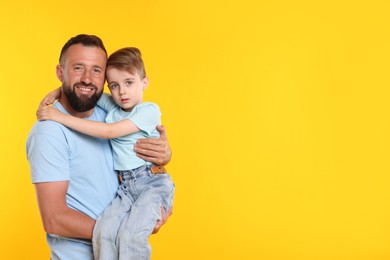 Photo of Family. Happy father and his son on yellow background. Space for text