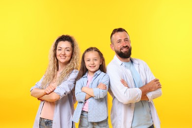 Photo of Portrait of happy family with crossed arms on yellow background