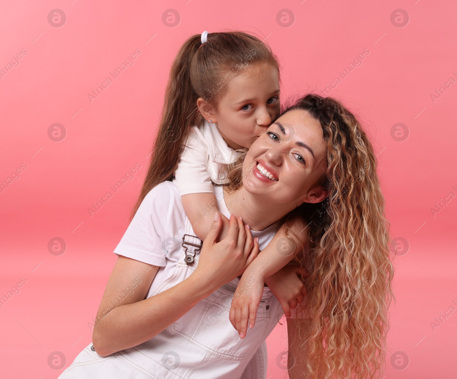 Family portrait of happy mother and her daughter on pink background Photo of Family portrait of happy mother and her daughter on pink background