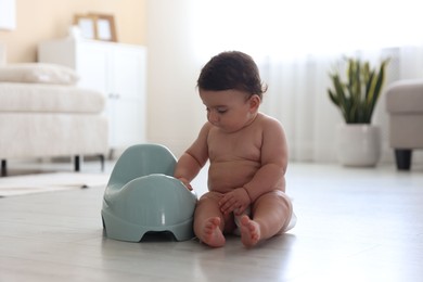 Photo of Cute little baby with potty on floor at home