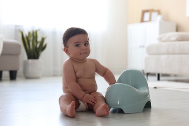 Photo of Cute little baby with potty on floor at home