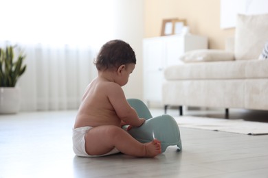 Photo of Cute little baby with potty on floor at home