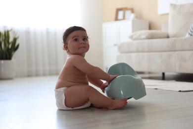 Photo of Cute little baby with potty on floor at home