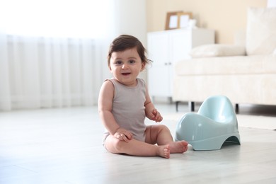 Photo of Cute little baby with potty on floor at home