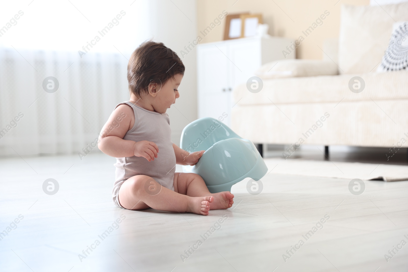 Photo of Cute little baby with potty on floor at home