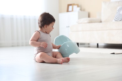 Photo of Cute little baby with potty on floor at home