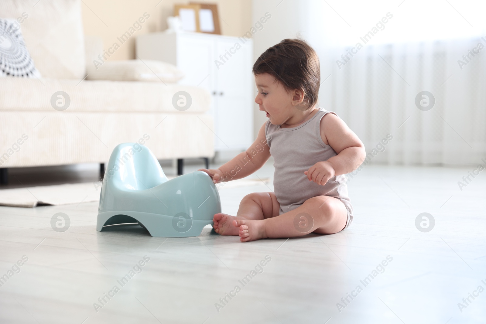 Photo of Cute little baby with potty on floor at home
