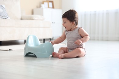 Photo of Cute little baby with potty on floor at home