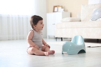 Photo of Cute little baby with potty on floor at home