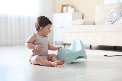 Photo of Cute little baby with potty on floor at home