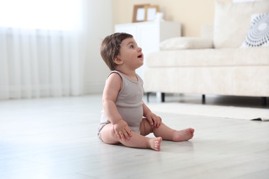 Photo of Cute little baby sitting on floor at home