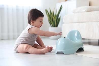 Photo of Cute little baby with potty on floor at home