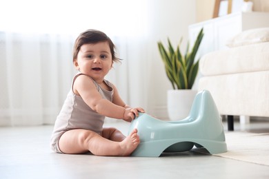 Photo of Cute little baby with potty on floor at home