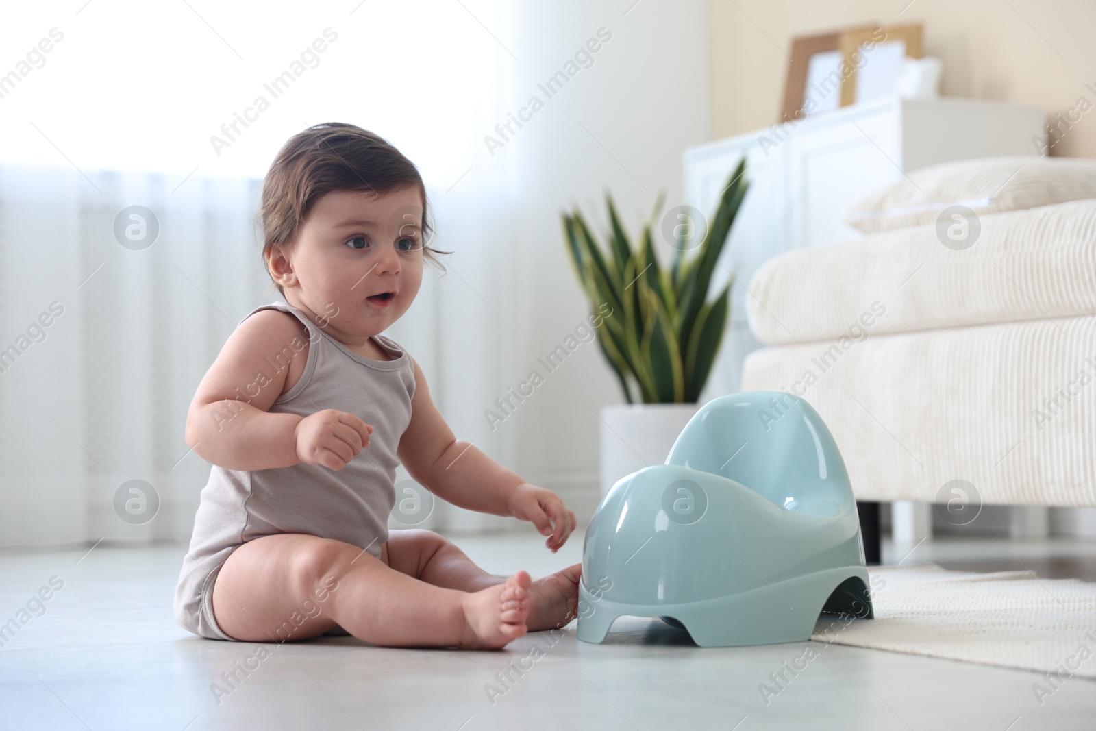 Cute little baby with potty on floor at home Photo of Cute little baby with potty on floor at home