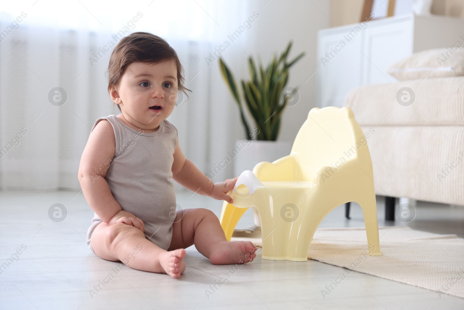 Cute little baby with potty on floor at home Photo of Cute little baby with potty on floor at home
