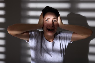 Photo of Emotional woman suffering from panic attack near wall indoors