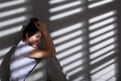 Photo of Emotional woman suffering from panic attack near wall indoors, space for text