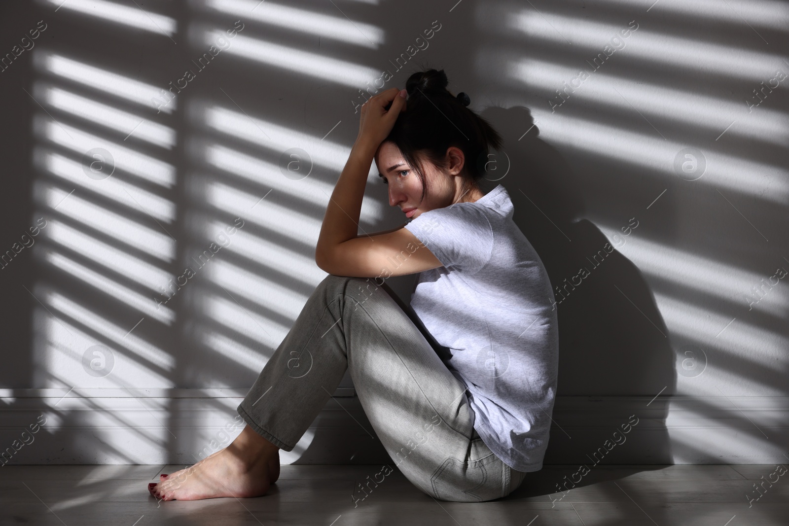Photo of Emotional woman suffering from panic attack near wall indoors