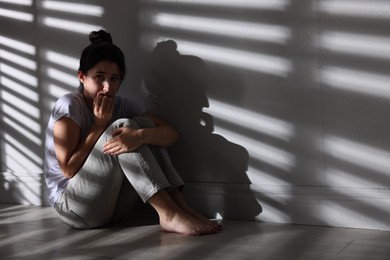 Photo of Emotional woman suffering from panic attack near wall indoors, space for text
