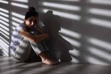 Photo of Emotional woman suffering from panic attack near wall indoors, space for text