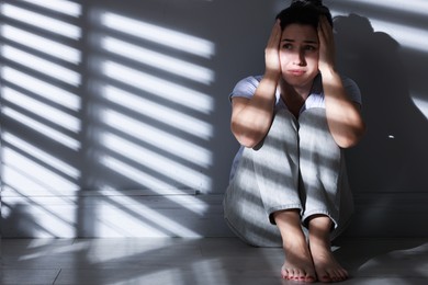 Photo of Emotional woman suffering from panic attack near wall indoors, space for text