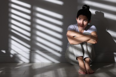 Photo of Emotional woman suffering from panic attack near wall indoors, space for text