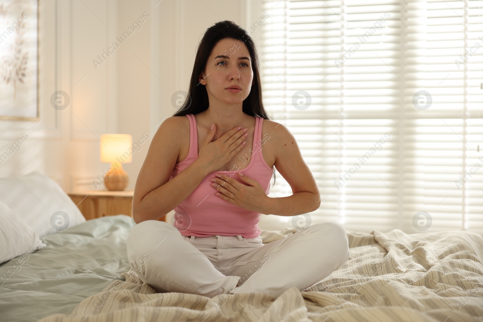 Panic attack. Woman breathing to calm down on bed at home Photo of Panic attack. Woman breathing to calm down on bed at home