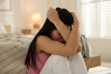 Photo of Emotional woman suffering from panic near bed indoors