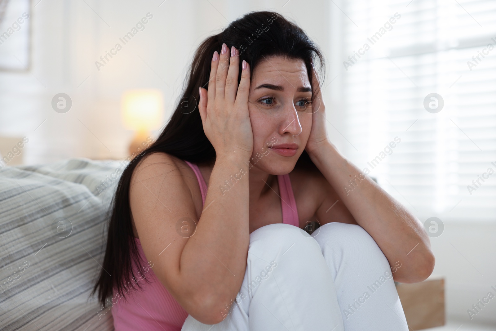 Emotional woman suffering from panic near bed indoors Photo of Emotional woman suffering from panic near bed indoors