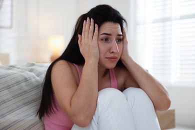 Photo of Emotional woman suffering from panic near bed indoors