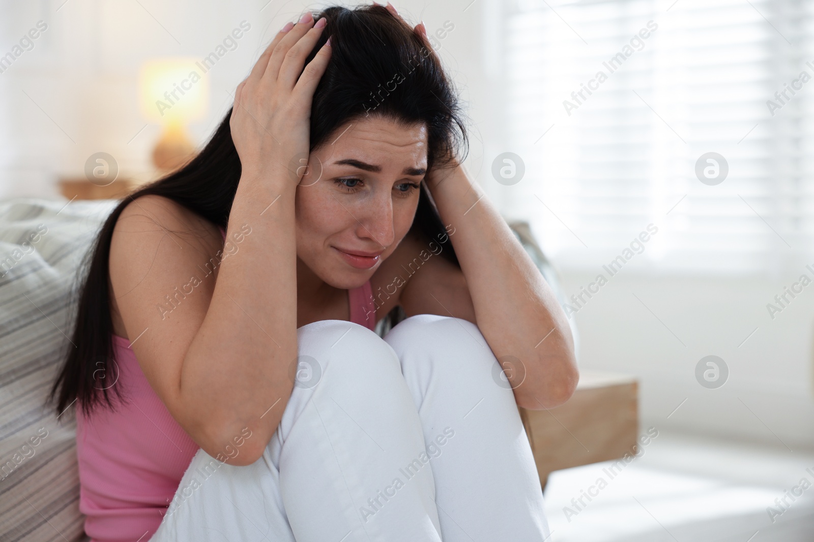 Photo of Emotional woman suffering from panic near bed indoors, space for text