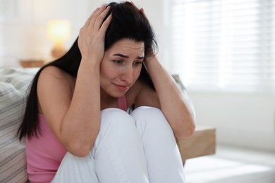 Photo of Emotional woman suffering from panic near bed indoors, space for text