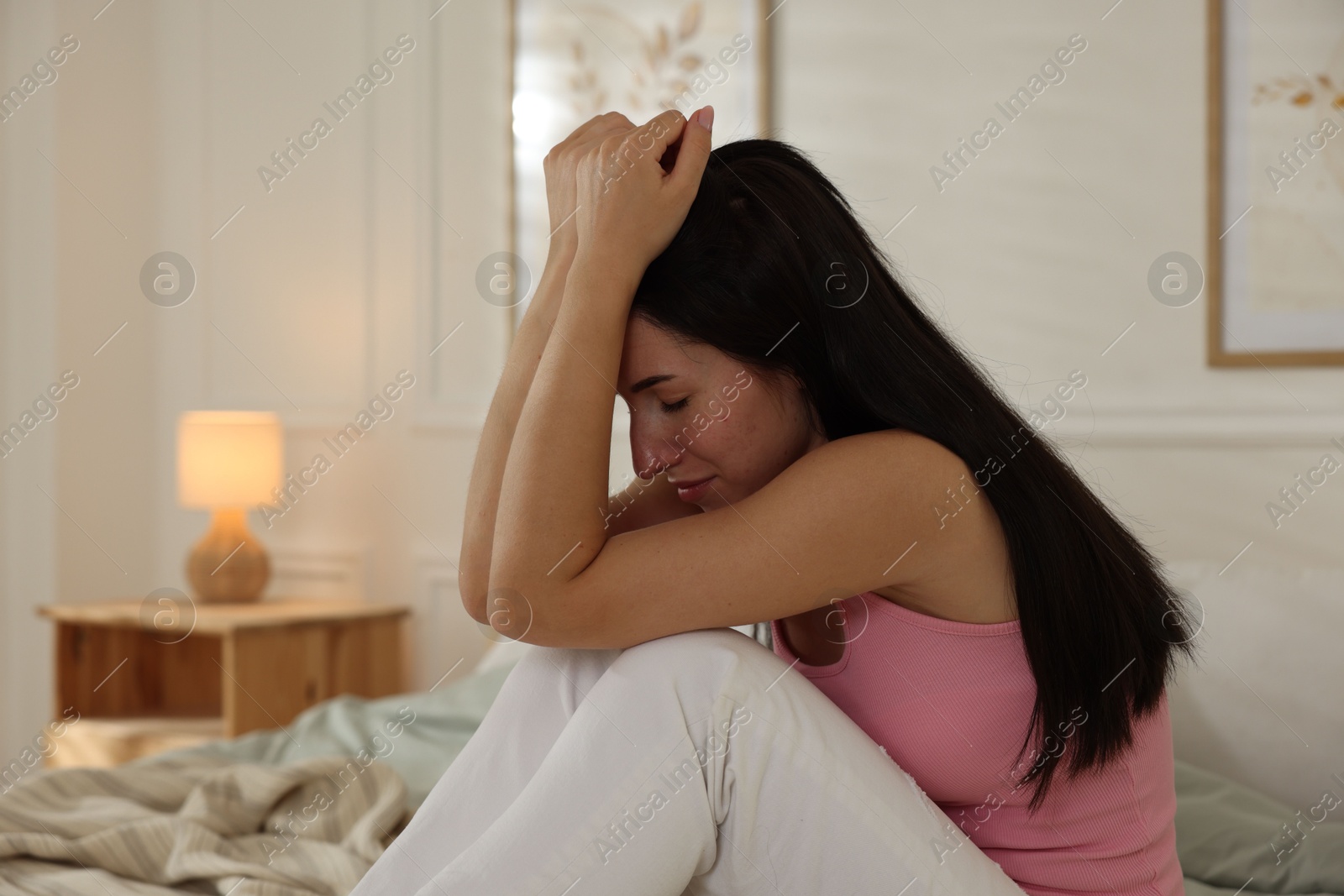 Emotional woman suffering from panic on bed indoors Photo of Emotional woman suffering from panic on bed indoors