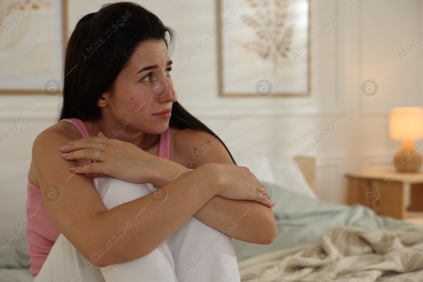 Photo of Emotional woman suffering from panic on bed indoors, space for text