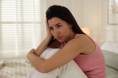 Photo of Emotional woman suffering from panic on bed indoors