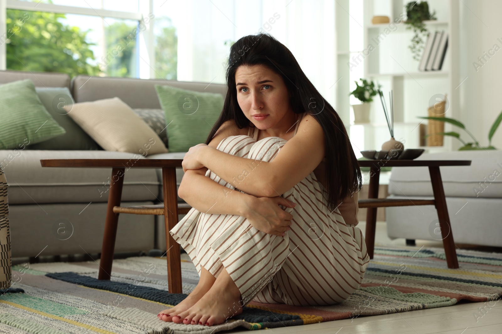 Photo of Emotional woman suffering from panic on floor indoors
